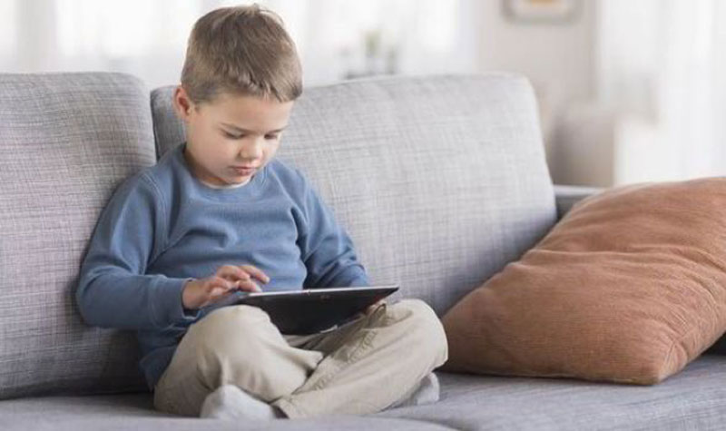 παιδί με το tablet καθισμένο στον καναπέ