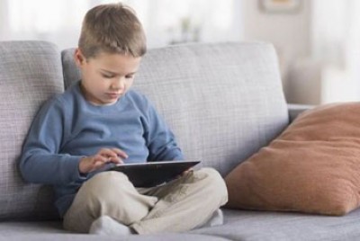 παιδί με το tablet καθισμένο στον καναπέ