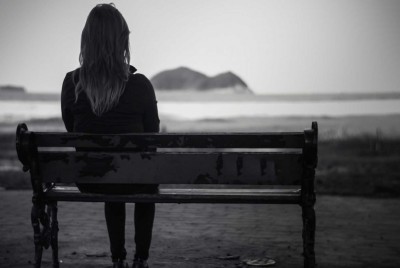 γυναίκα κάθεται σε ένα παγκάκι με θέα τη θάλασσα