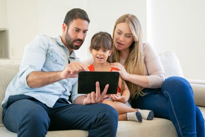 κορίτσι και μητέρα που είναι καθισμένες στον καναπέ μπροστά από ένα λάπτοπ