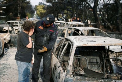 ψυχολογικά φορτισμένη γυναίκα που κλαίει στον ώμο ενός πυροσβέστη κοιτάζοντας το καμένο αμάξι της μετά καταστροφικό γεγονός