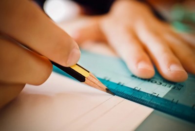 μαθητής χρησιμοποιεί μολύβι και χάρακα σε τετράδιο