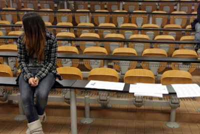 φοιτήτρια κάθεται πάνω σε θρανίο πανεπιστημίου