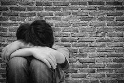έφηβος με σκυμμένο κεφάλι ανάμεσα στα χέρια του 
