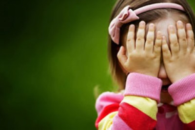 κοριτσάκι με χρωματιστή μπλούζα που κλείνει τα μάτια με τα χέρια της γιατί ντρέπεται