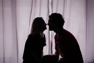αγόρι και κορίτσι ετοιμάζονται να φιληθούν μπροστά από ένα παράθυρο κλειστό με κουρτίνα