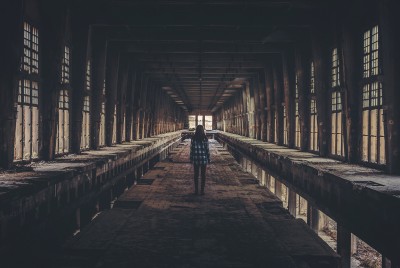 άνθρωπος να περπατάει σε ένα βιομηχανικό χώρο με έλαχιστο φως 