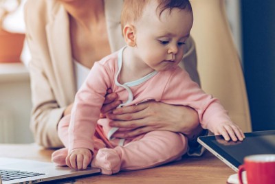 εργαζόμενη μητέρα με το μωρό μπροστά από το λάπτοπ της