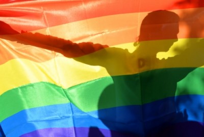 άτομο κρατά σημαία με τα χρώματα του ουράνιου τόξου