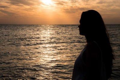 γυναίκα στην παραλία κοιτάζει το ηλιοβασίλεμα