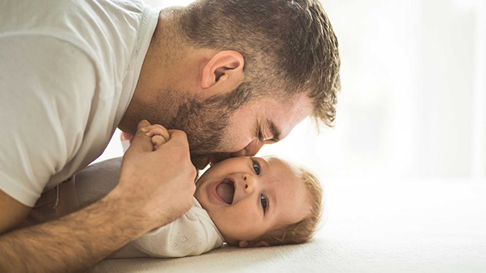 πατέρας φιλάει το μωρό ενώ αυτό γελάει