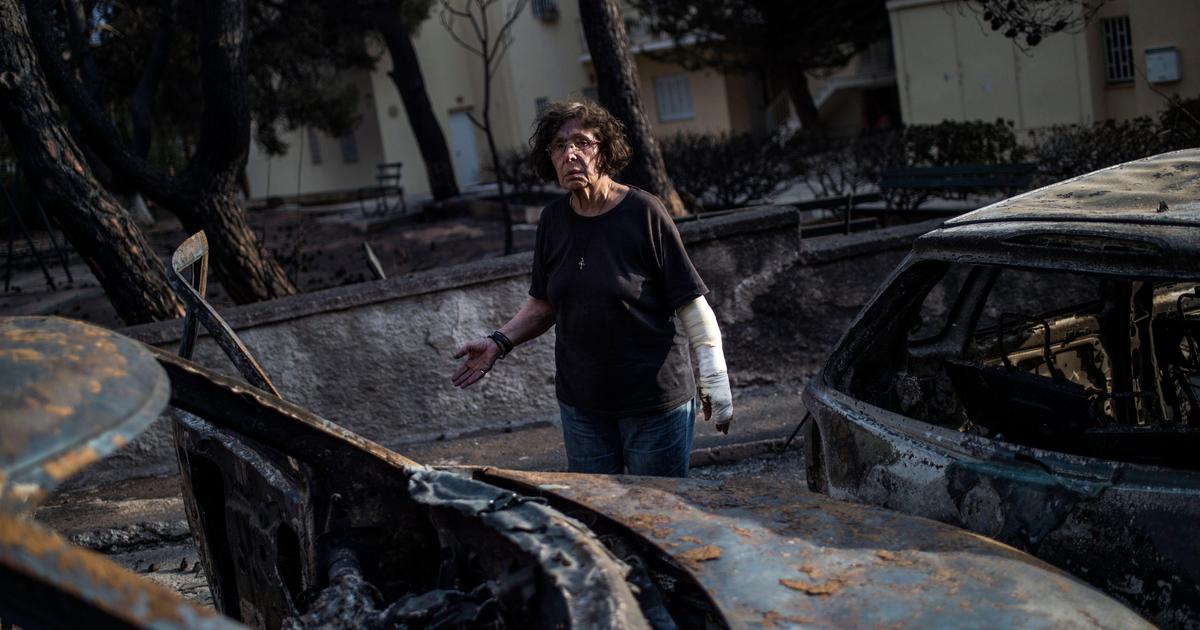 ηλικιωμένη γυναίκα μπροστά από καμένα αυτοκίνητα