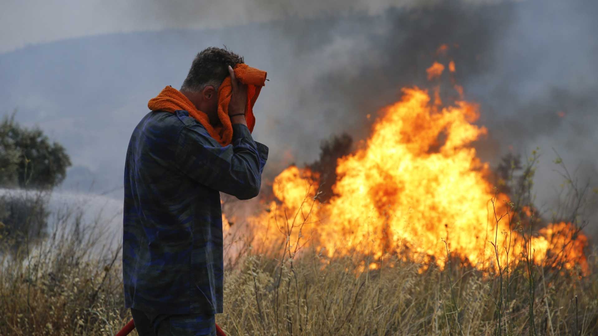 άνδρας που προστατεύει το πρόσωπό του με φωτιά να καίει πίσω του