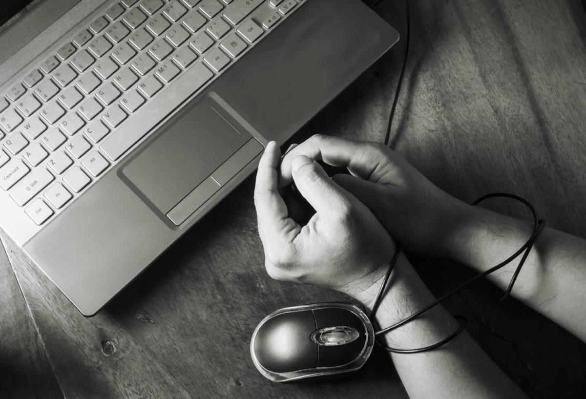 δύο χέρια δεμένα από το καλώδιο ενός mouse μπροστά από ένα πληκτρολόγιο